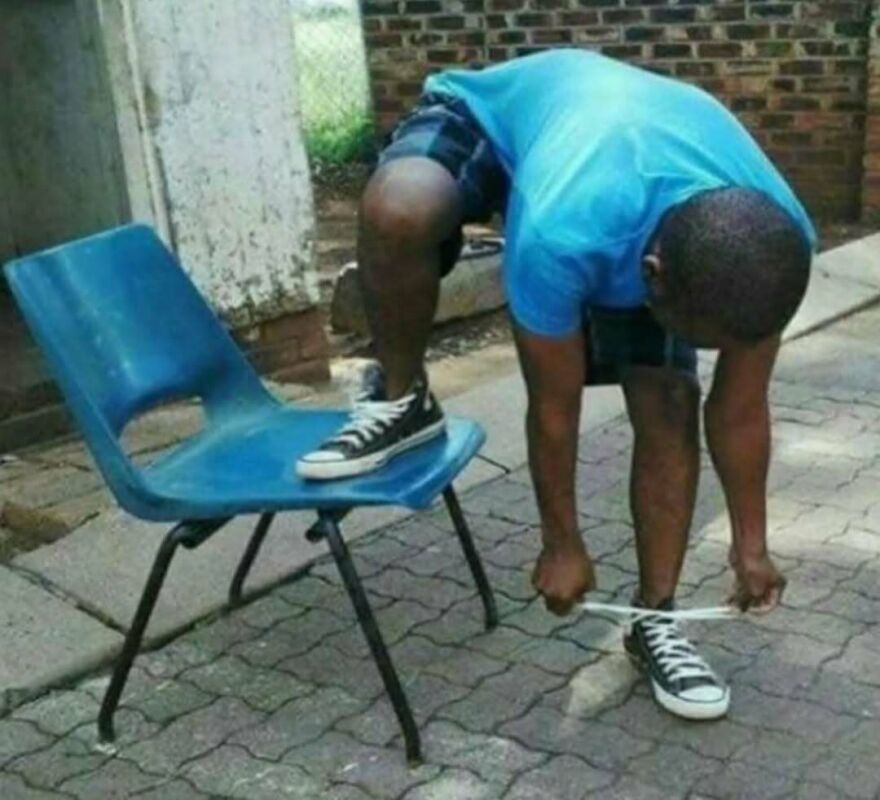 Person in blue shirt bending over to tie shoelaces with one foot on a blue chair in a bizarre yet hilarious scene