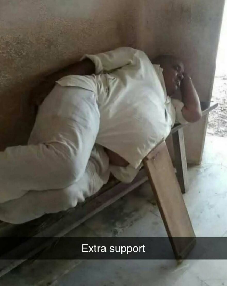 Man lying on a bench using a wooden plank for extra support in a bizarre yet hilarious moment captured indoors.