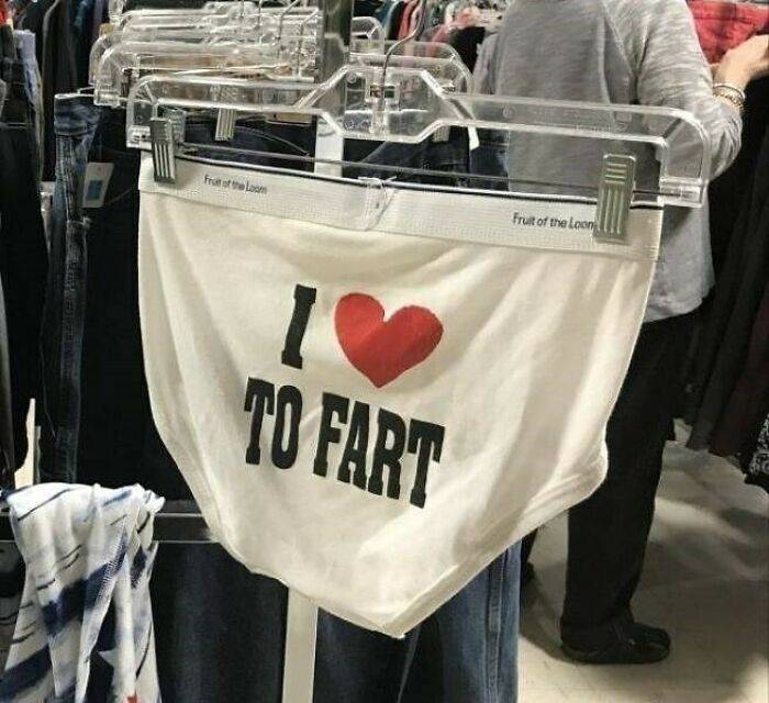 Secondhand novelty underwear with funny text hanging on a rack among other secondhand clothing finds.
