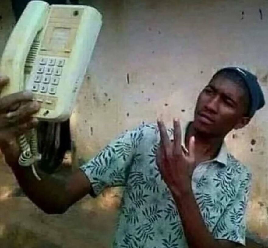 Man holding an old landline phone confused, showcasing bizarre and hilarious pics that might make you do a double take