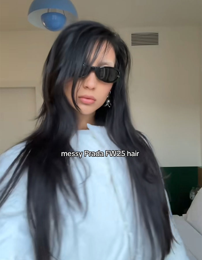 Young woman with long messy dark hair and sunglasses modeling the trendy depression hairstyle popular with Gen Z and millennials.