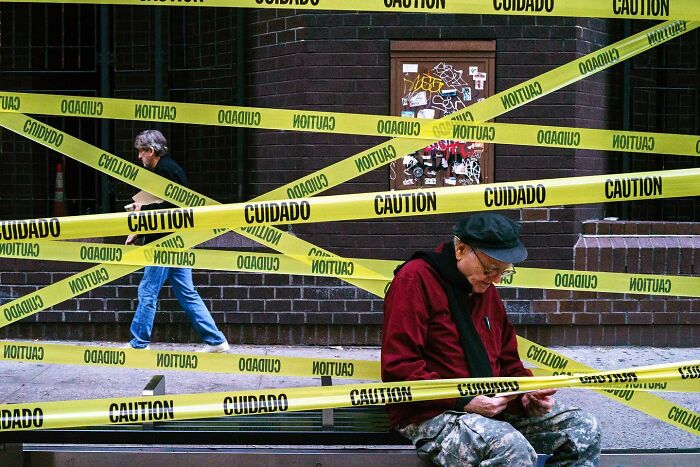 Street photographer captures magical city life with people interacting around caution tape creating unique urban coincidences.