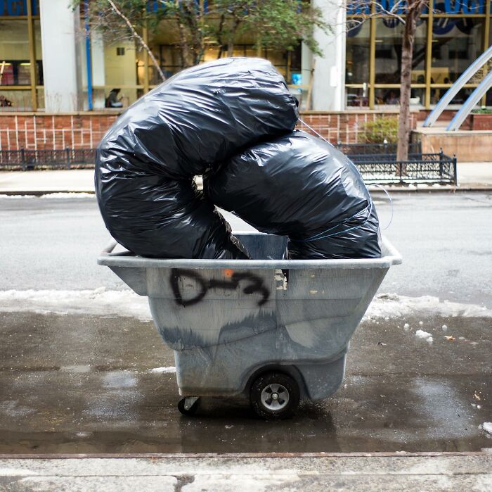Street photographer captures a magical city life moment with large black trash bags creating a unique urban coincidence.