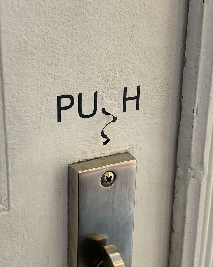 Close-up of a door with a worn push sign and metal handle, highlighting a street photographer's magical urban coincidence.