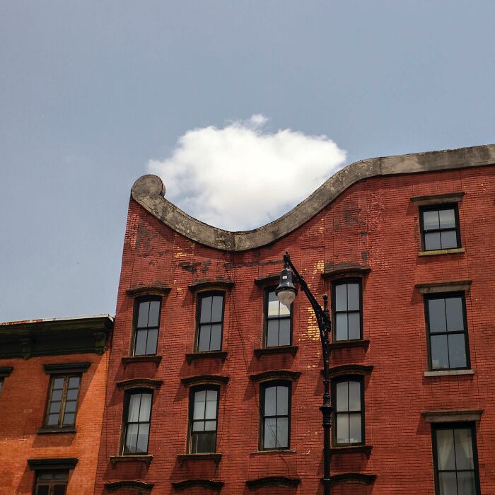 Red brick buildings with a street lamp and a cloud perfectly aligned, capturing magical street photography moments.