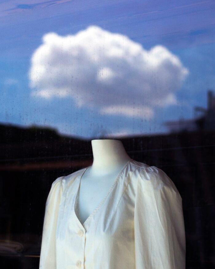 Headless mannequin in a white blouse with a cloud perfectly aligned above, capturing magical street photography coincidence.