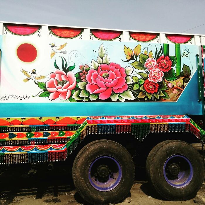 Vibrant truck decorated with colorful, intricate patterns featuring flowers and birds showcasing artist's stunning car art.