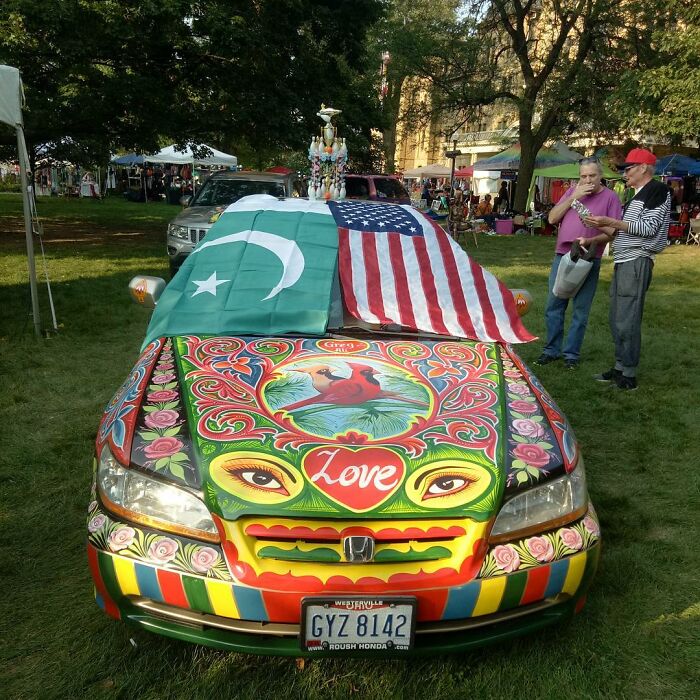 Car painted with colorful, intricate patterns, featuring vibrant designs and flags, showcasing stunning works of art by an artist.