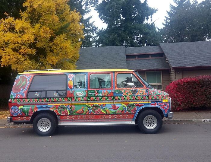 Van covered in colorful, intricate patterns showcasing the artist's unique automotive artwork on a suburban street.