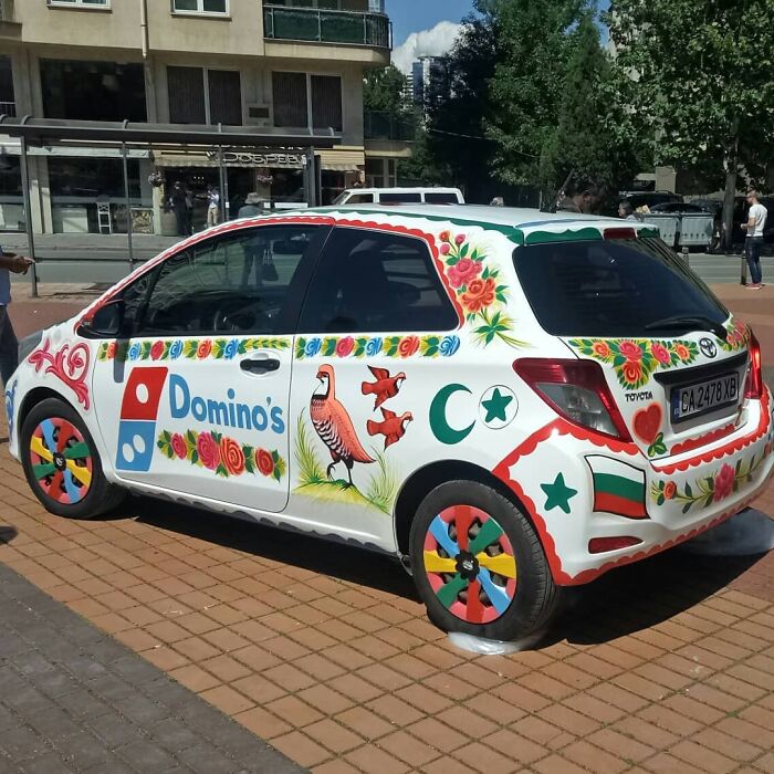 Car decorated with colorful, intricate patterns and floral designs, showcasing unique artistic work on vehicle surfaces.