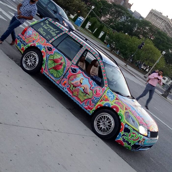 Colorful car painted with intricate patterns and vibrant wildlife designs, showcasing the artist's unique work of art.