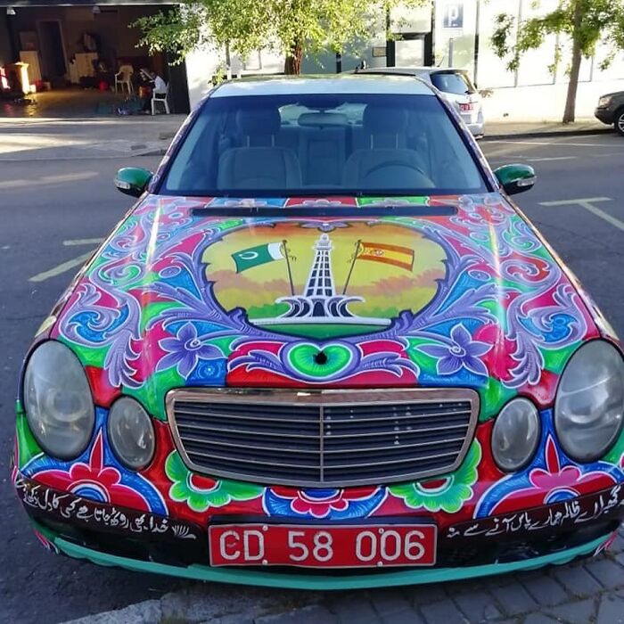 Car covered in colorful, intricate patterns transforming it into a stunning work of art with vibrant detailed designs.