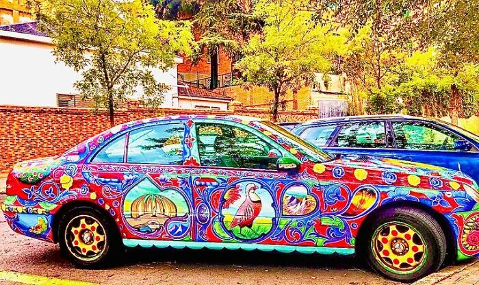 Colorful car transformed into stunning work of art with intricate patterns by talented artist in outdoor setting