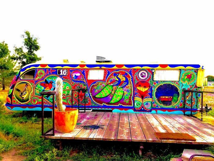Colorful, intricate patterns transform this trailer into a vibrant work of art featuring birds and floral designs outdoors.