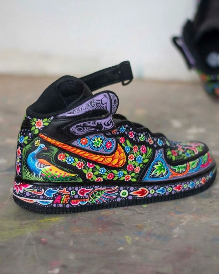 Colorful sneaker featuring intricate patterns and detailed artwork of flowers and a peacock on black base.