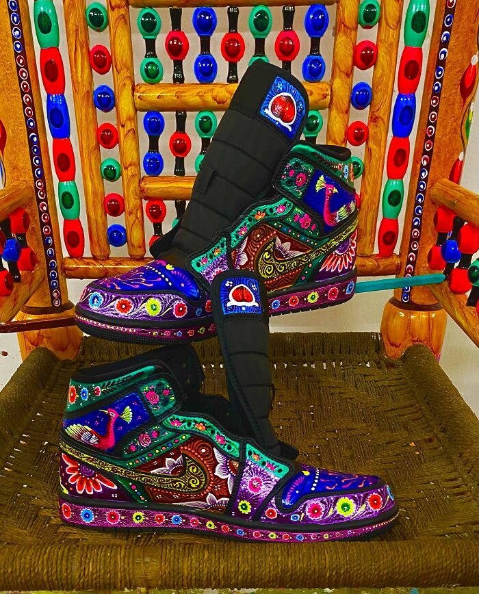 Intricately patterned colorful shoes displayed on a woven seat, showcasing vibrant artistic designs and detailed artwork.