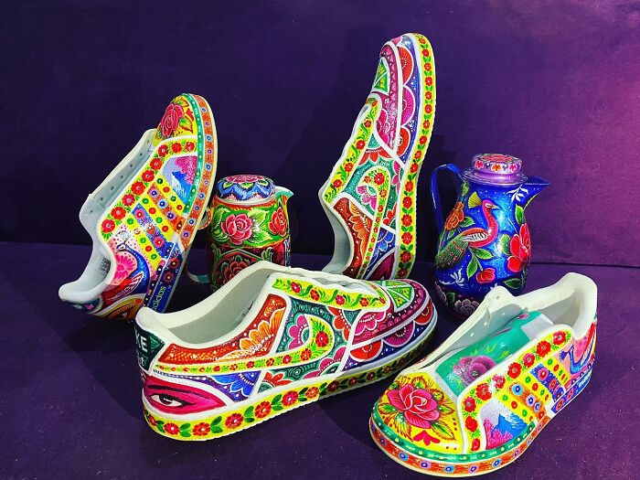 Colorful shoes with intricate hand-painted patterns displayed alongside matching painted pottery on a dark purple background.
