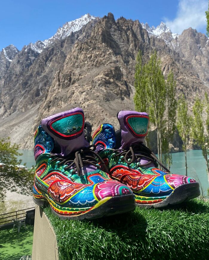 Colorful shoes featuring intricate patterns displayed outdoors with mountains and trees in the background.