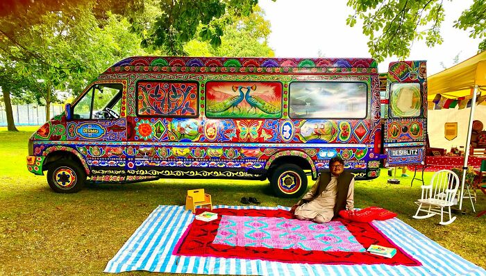 Artist showcasing a colorful, intricate patterned van in a park, turning cars into stunning works of art.