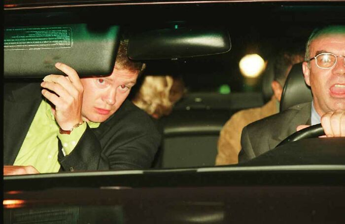 Two famous people in a car at night, one adjusting the sun visor, captured in a last known photo.