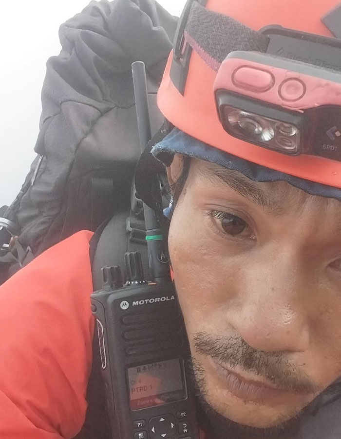 Rescue worker wearing helmet and radio during recovery mission at 1600ft-deep active volcano, hero guide recovers tourist's body