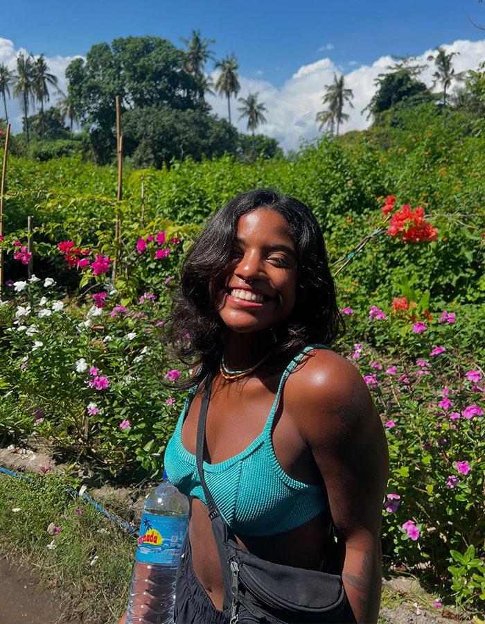 Young woman smiling outdoors in a garden, related to hero guide recovering tourist's body from active volcano.