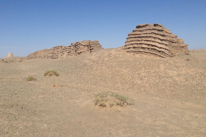 Ancient landmark ruins in a desert landscape captured from an unexpected angle showing layered stone structures.