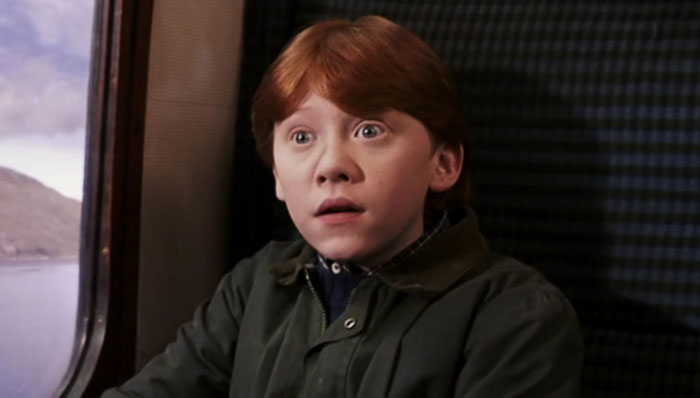 Young red-haired boy seated by a train window, looking surprised, referencing Harry Potter incest scene controversy.