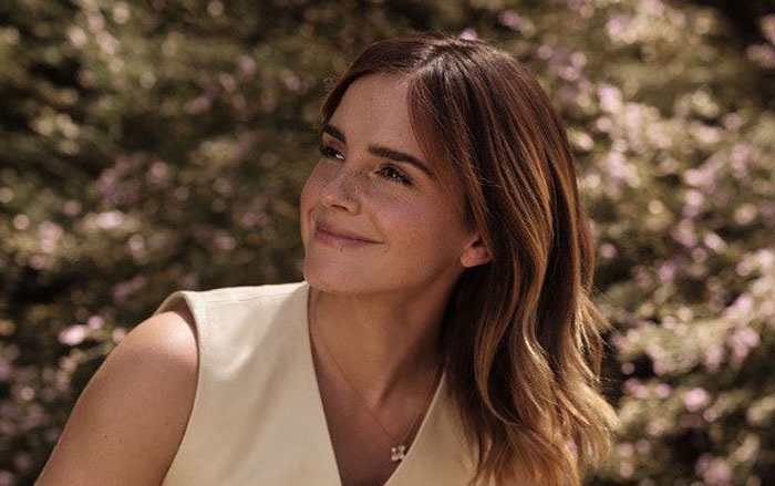 Emma Watson outdoors smiling, discussing Harry Potter and reactions to the controversial incest scene in a recent interview.