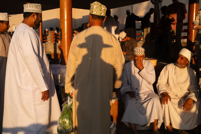 Photographer travels the world capturing candid street moments of men in traditional attire filled with emotion at sunset.