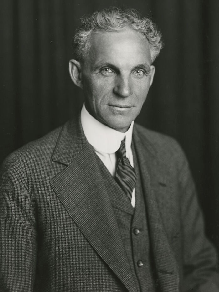 Black and white portrait of a confident late bloomer millionaire in a vintage suit and tie against a dark background