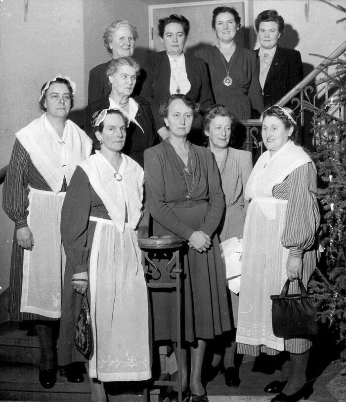 Group of 1940s housewives wearing aprons and dresses, representing iconic women who held the world together during the era.