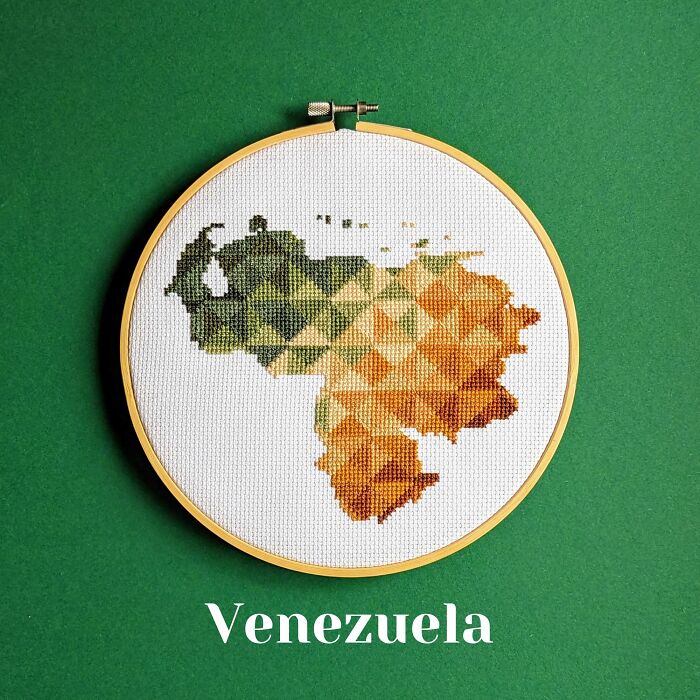 Cross-stitched map of Venezuela with geometric patterns in green and orange shades on white fabric.