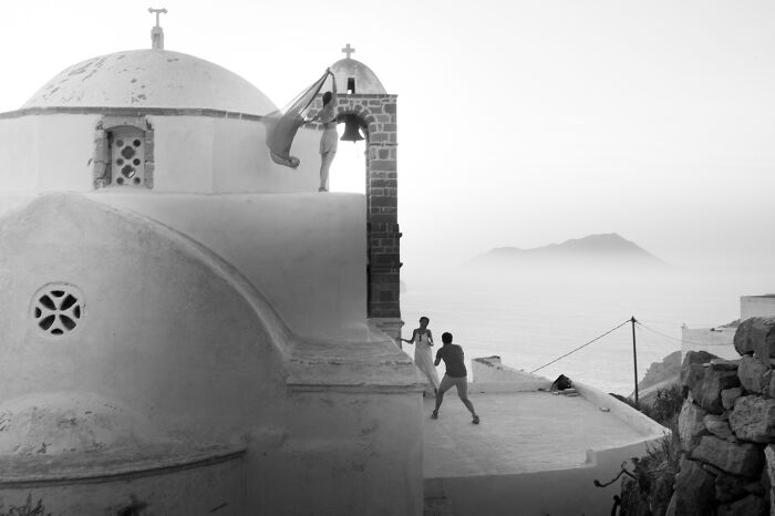 Black and white cinematic photo by Adriana Ferrarese capturing a serene moment on a rooftop with a scenic ocean view.