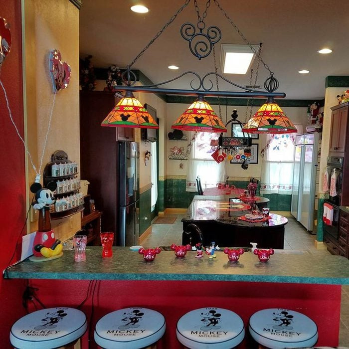 Kitchen interior with unhinged real estate listing style featuring Mickey Mouse décor and eclectic colorful lighting.