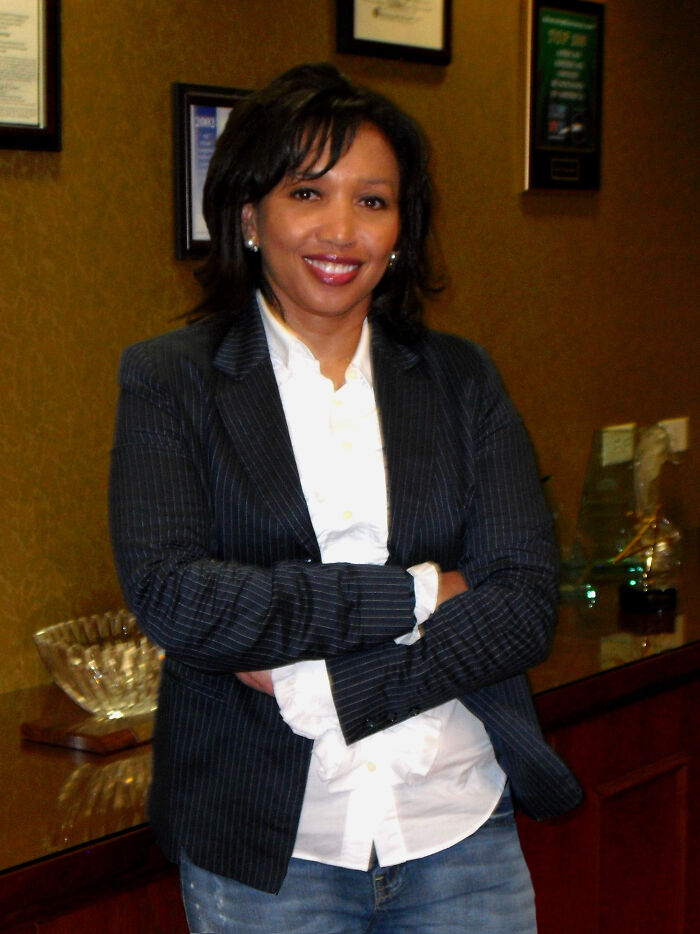 African American woman in business casual attire standing confidently in an office highlighting inventions by people of color.