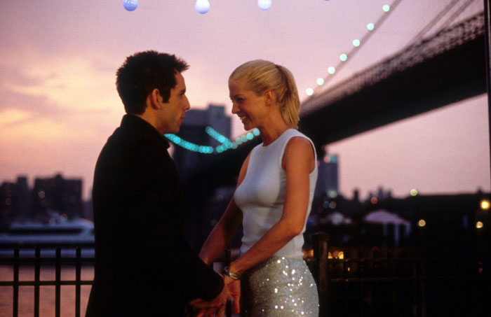 Famous 90s actress aged 53 smiling with a man during a rare public outing at sunset near a city bridge.