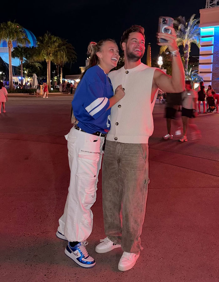 JoJo Siwa smiling with a man taking a selfie outdoors at night, highlighting JoJo Siwa dropped by major record label. JoJo Siwa smiling with a man taking a selfie outdoors at night, highlighting JoJo Siwa dropped by major record label.