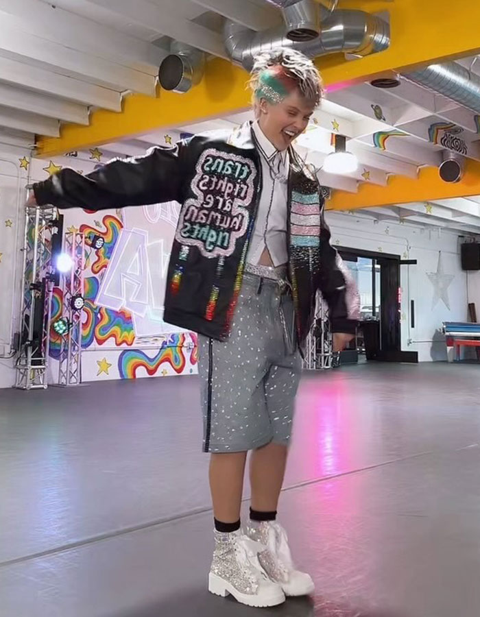 JoJo Siwa dancing in a colorful studio wearing sparkly jacket and silver boots after record label drop news. JoJo Siwa dancing in a colorful studio wearing sparkly jacket and silver boots after record label drop news.