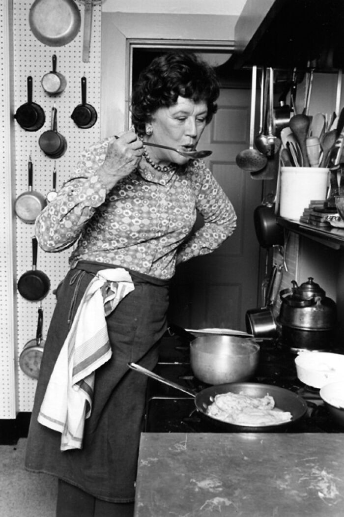 Woman cooking in a kitchen tasting food with a spoon, illustrating late bloomers who became millionaires through culinary success.
