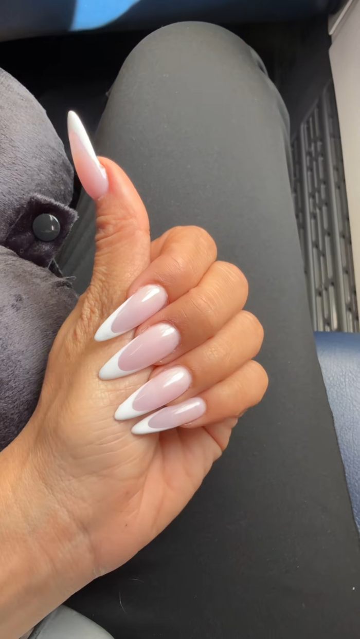 Close-up of a hand with long French manicure nails, highlighting style favored by Aussie influencer in the US.