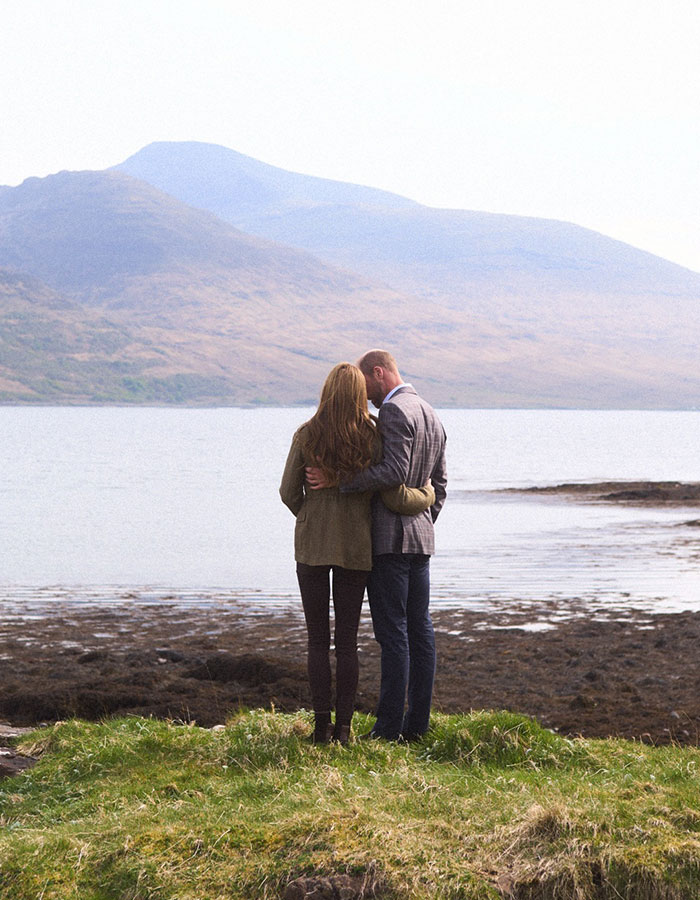 Kate Middleton and Prince William standing on grass by a lake with hills, celebrating Prince William's birthday.