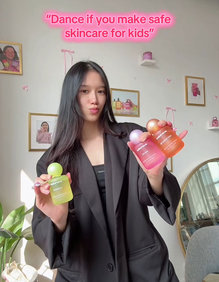 Young woman holding colorful skincare bottles highlighting concerns about social media trend impacting pre-teen girls&rsquo; health.