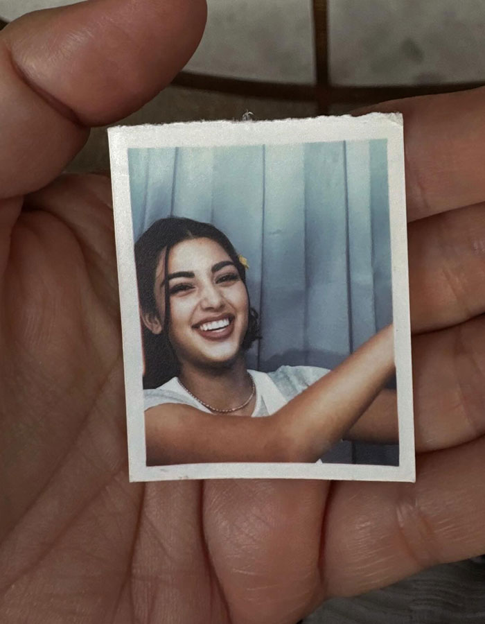 Hand holding a vintage photo of a smiling woman, sparking discussions about Kim Kardashian plastic surgeries.