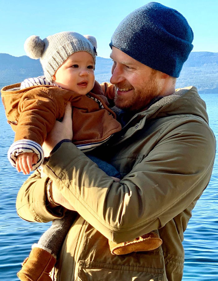 Prince Harry holding baby son near lake, illustrating King Charles shares heartfelt Fathers Day message and call for reconciliation.