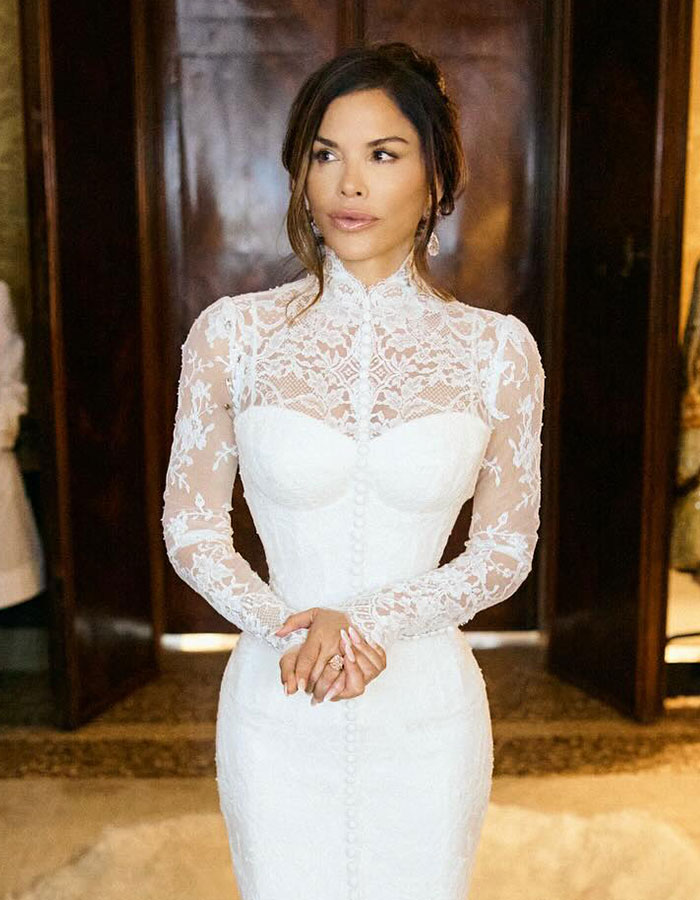 Woman in a white lace wedding dress breaking major wedding rule at an elegant celebration event indoors.