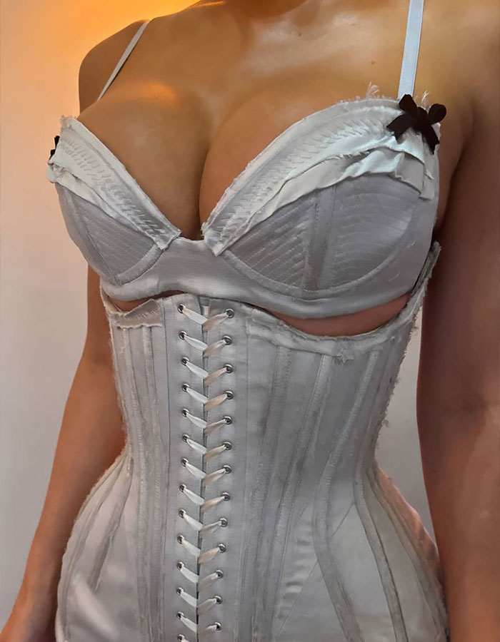 Kylie Jenner wearing a white corset dress that appears distressed, breaking a major wedding rule at a celebration.