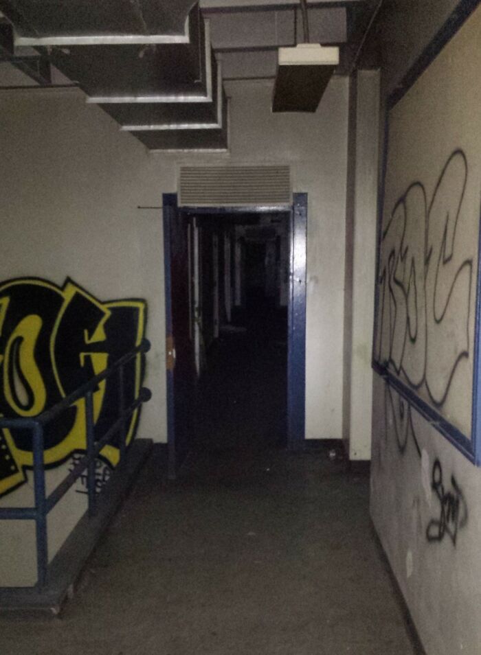 Dark abandoned hallway with graffiti on walls, showing eerie atmosphere experienced by explorers during creepy escapades.