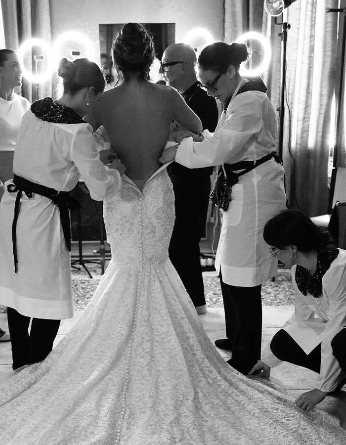 Lauren S&aacute;nchez getting help from staffers in a bridal gown, with elves photobombing, creating a viral moment.