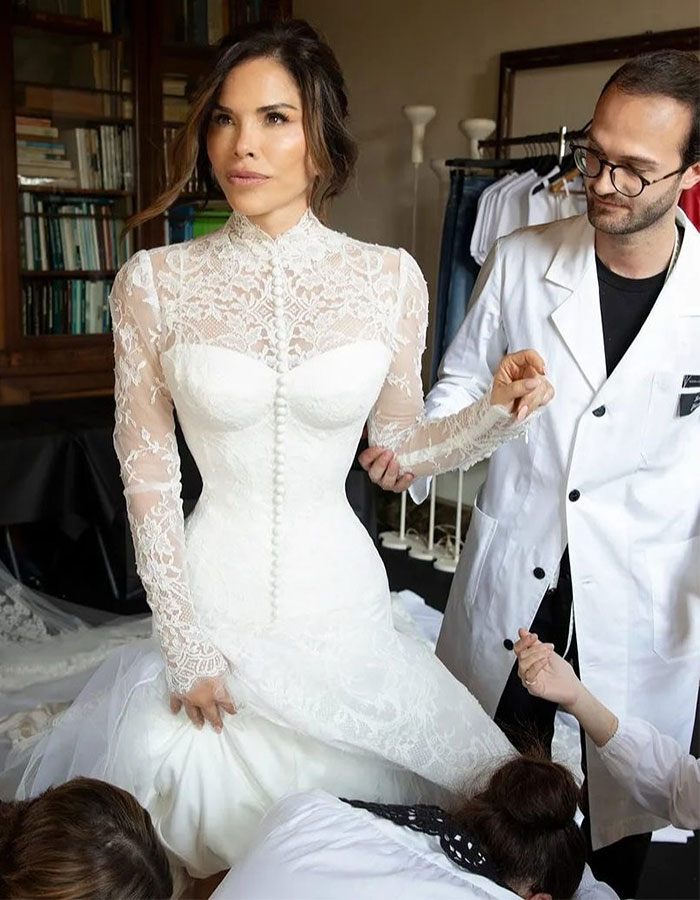 Lauren S&aacute;nchez in a bridal gown being assisted by staffers during a fitting, capturing an uncomfortable photobomb moment.